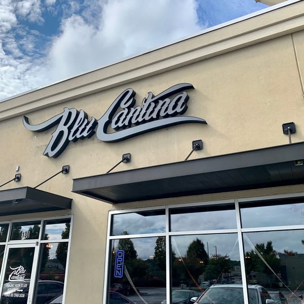 Exterior view of Blu Cantina restaurant with its sign, windows, and awnings under a cloudy sky.