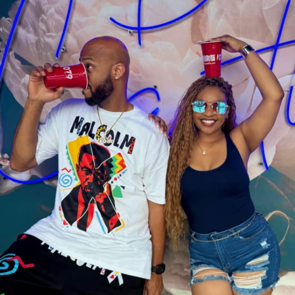 A man and woman posing with red cups, the woman balancing one on her head.