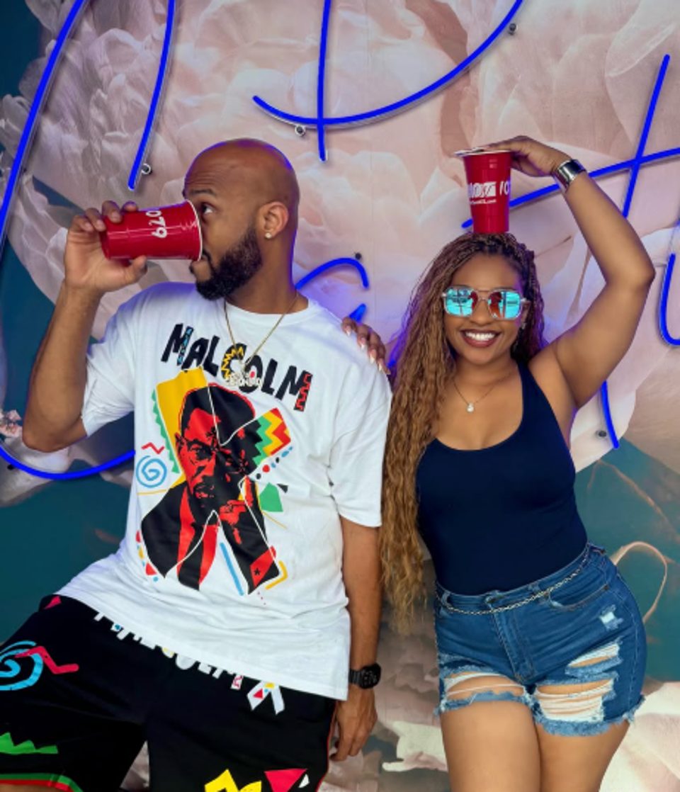 A man and woman posing with red cups, the woman balancing one on her head.